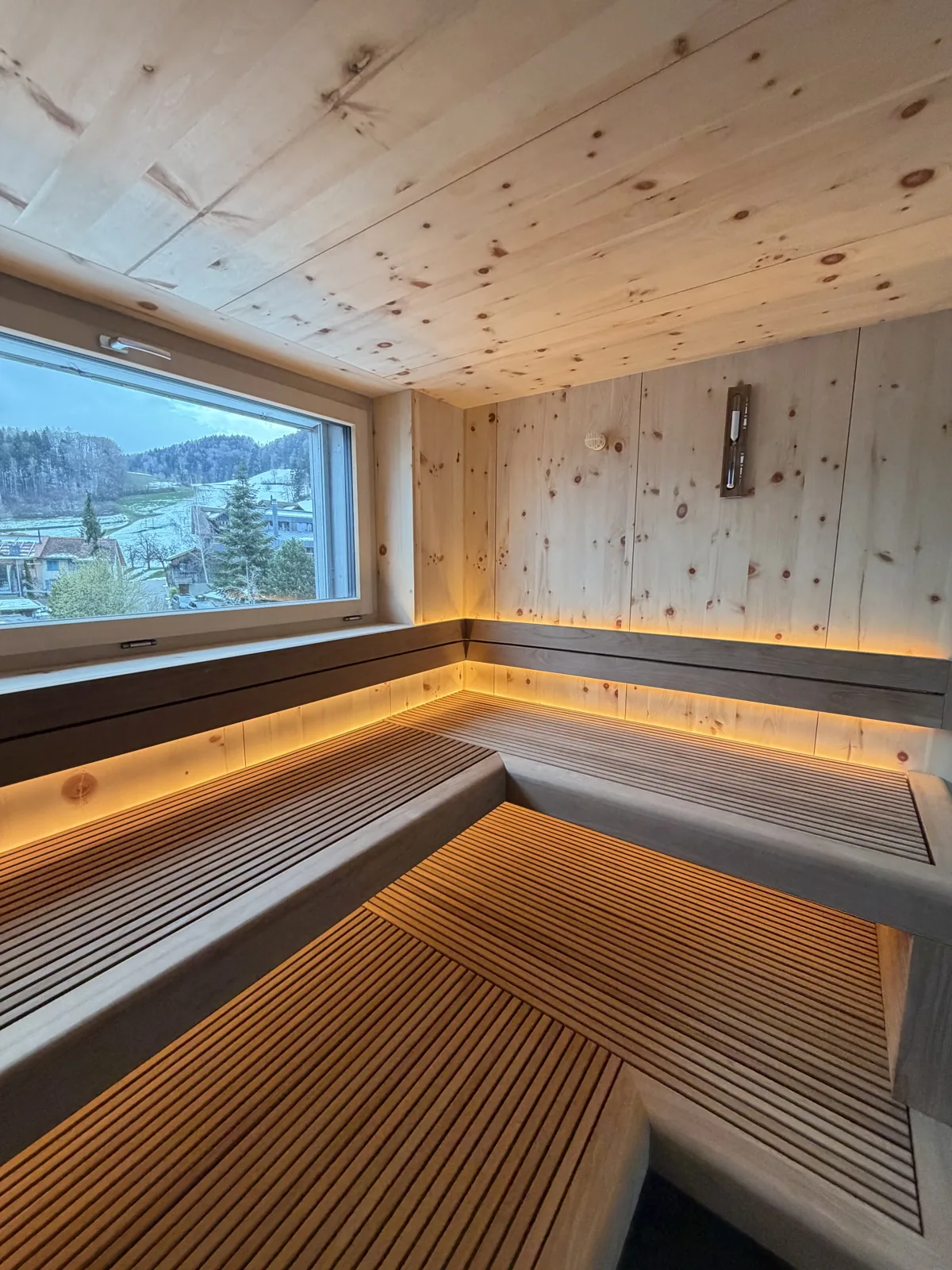 Private Sauna aus Arvenholz mit Fenster und indirekt beleuchteten Liegen