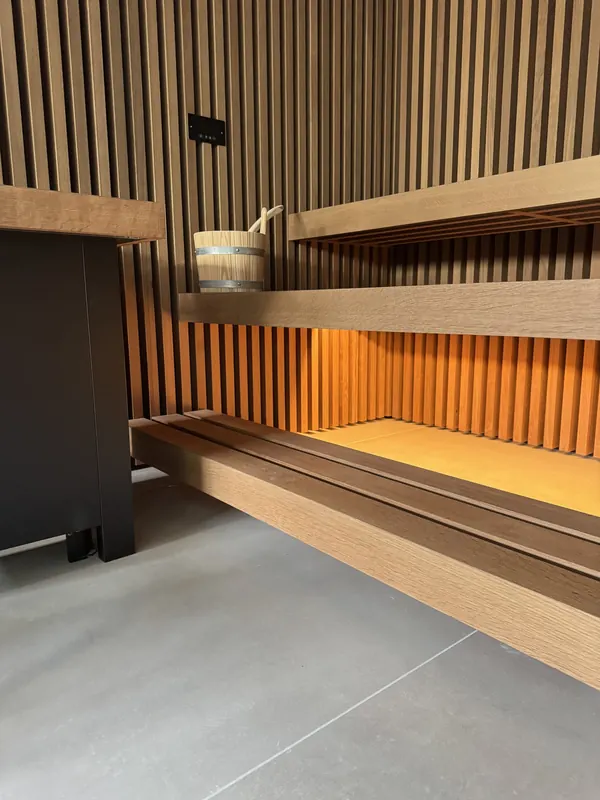 Sauna mit Lamellenwand aus Eiche, schwebenden Bänken und warmem Unterbaulicht