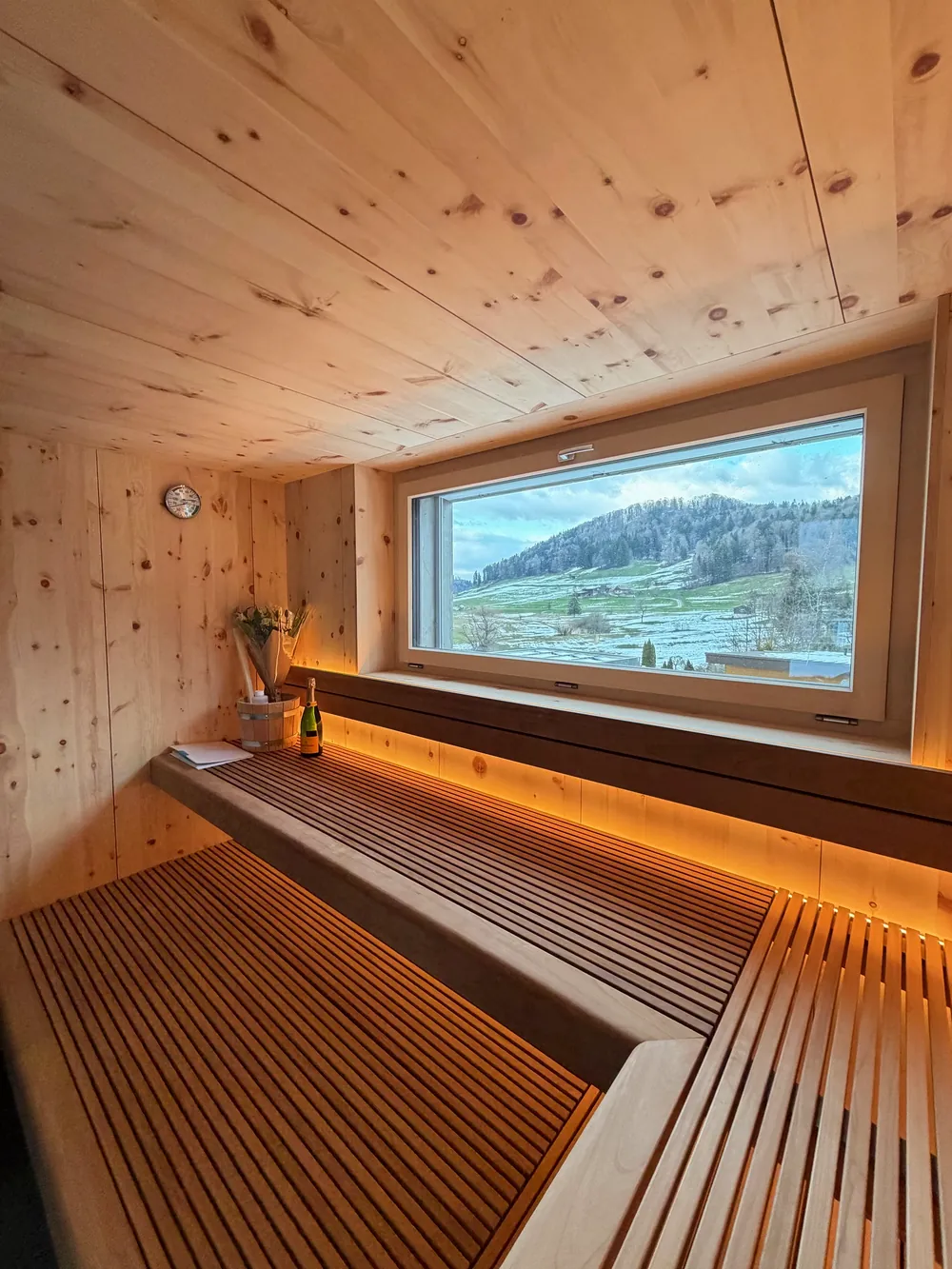 Arvensauna mit Panoramafenster und Blick ins verschneite Tal, Liegebänke mit Lichtband