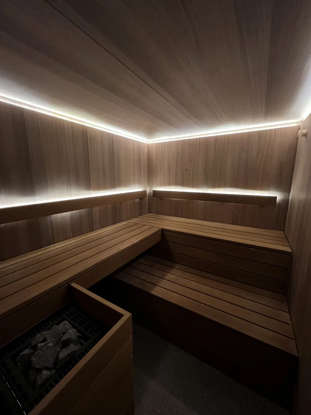 Sauna in Liechtenstein mit dunklem Holz, Eckbank und umlaufendem Lichtband