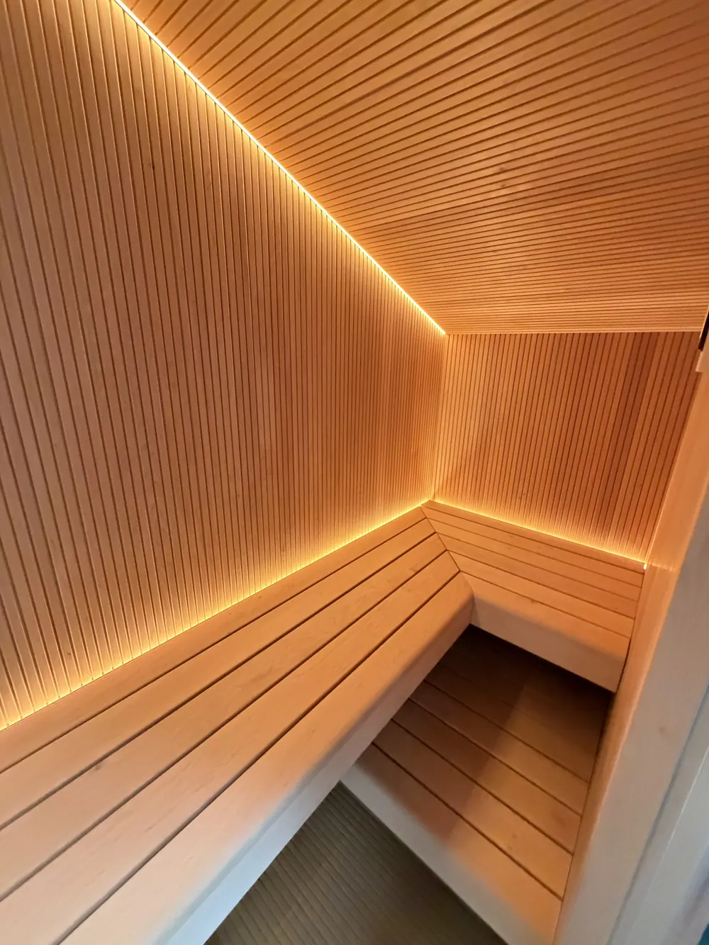 Eckbank in der Sauna mit indirekter LED-Beleuchtung entlang der Wand