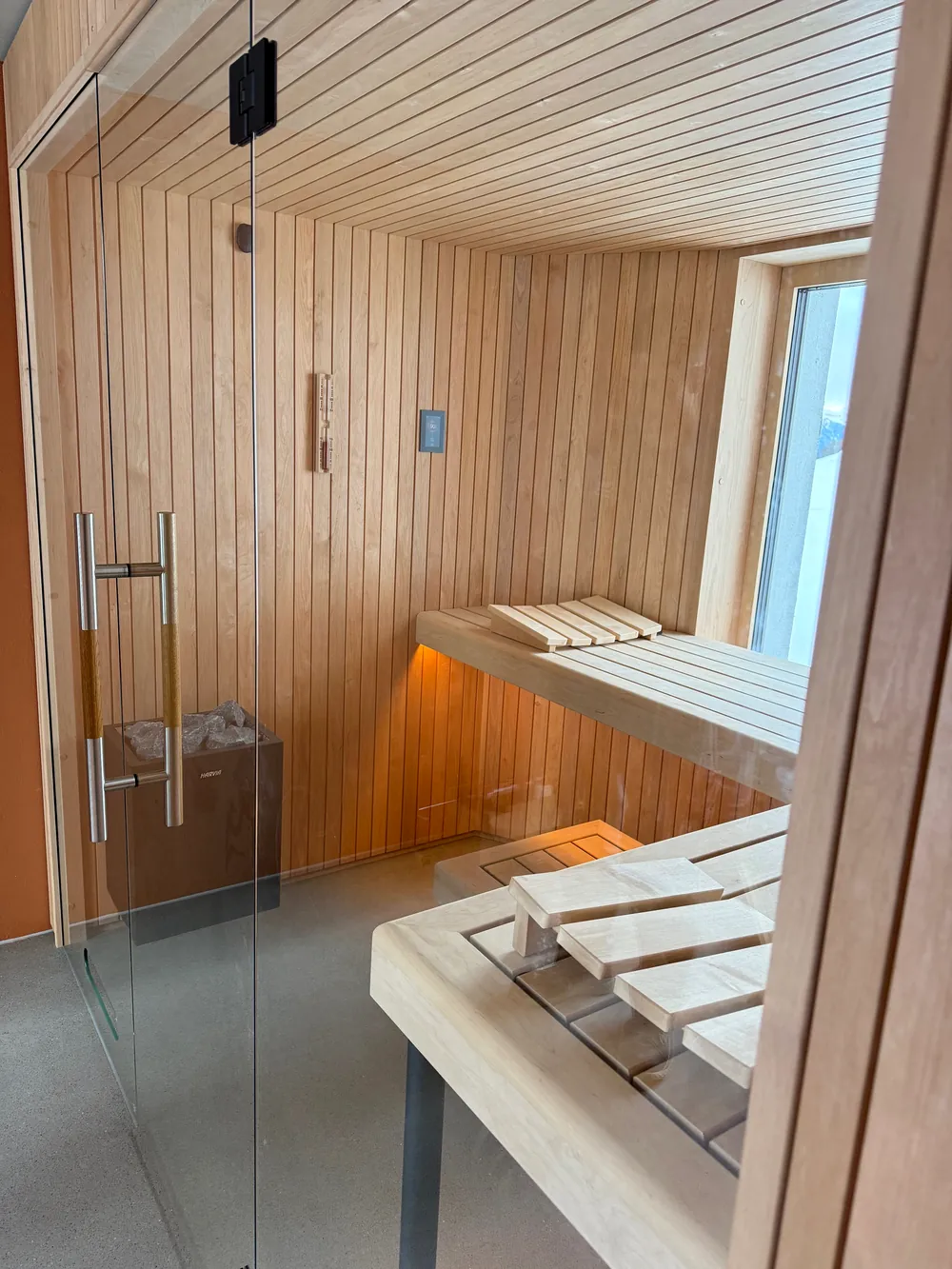 Sauna mit Glasfront, hellem Holz, Harvia-Saunaofen und Fenster