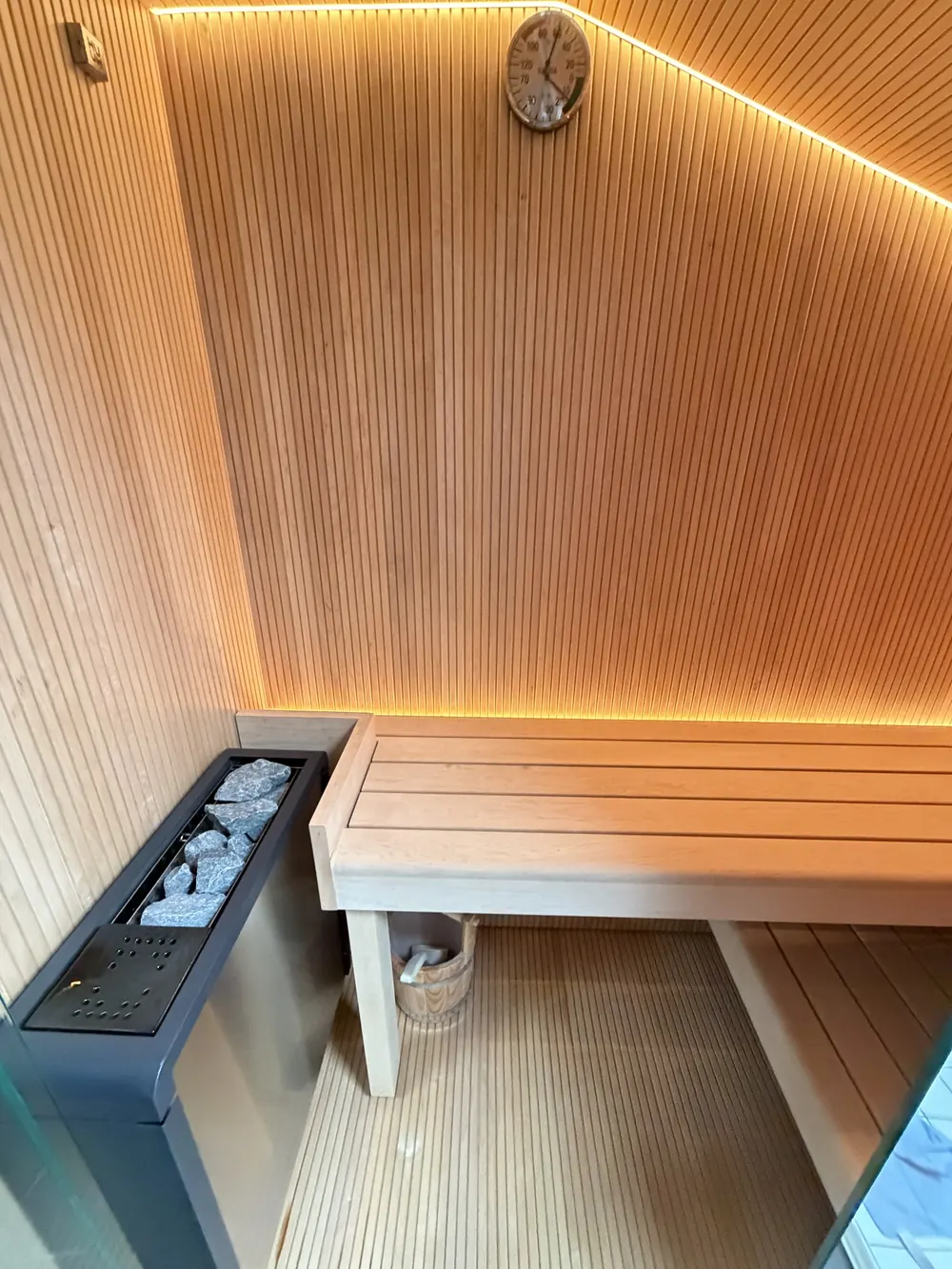 Saunaofen mit Steinen neben der Sitzbank, Hygrometer an der Wand